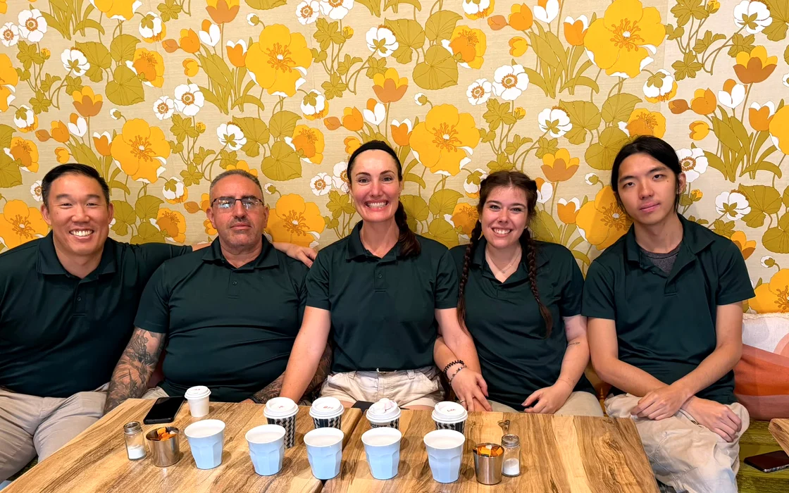 Five members of the Gumnut Cleaning crew in uniform, sitting together around a table
